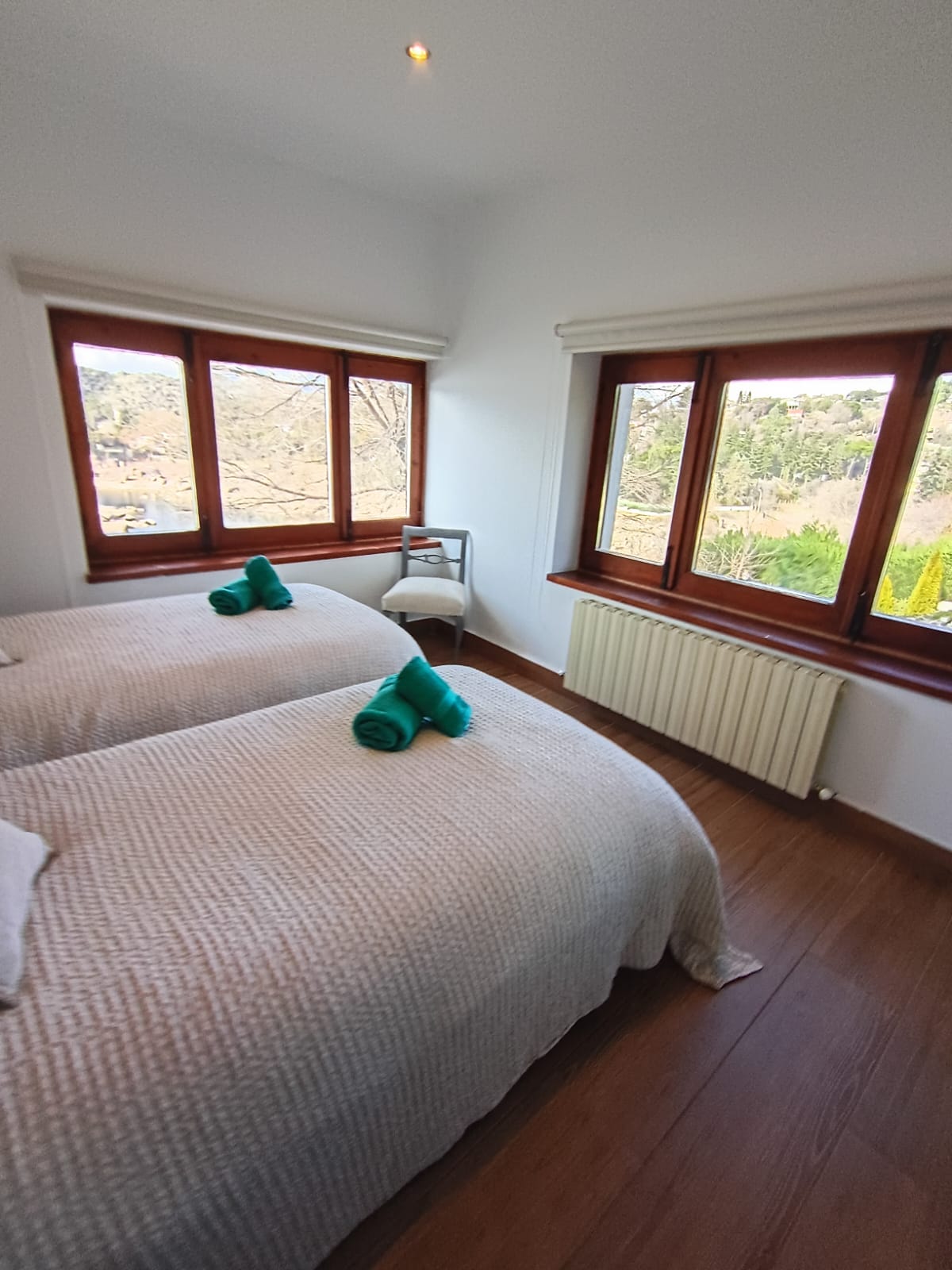 Dormitorio listo para el huésped: cama hecha, toallas dobladas y vistas al exterior